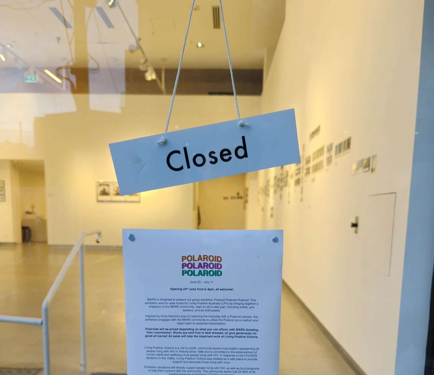 Gallery entry documentation with a closed sign and installation visible beyond glass.