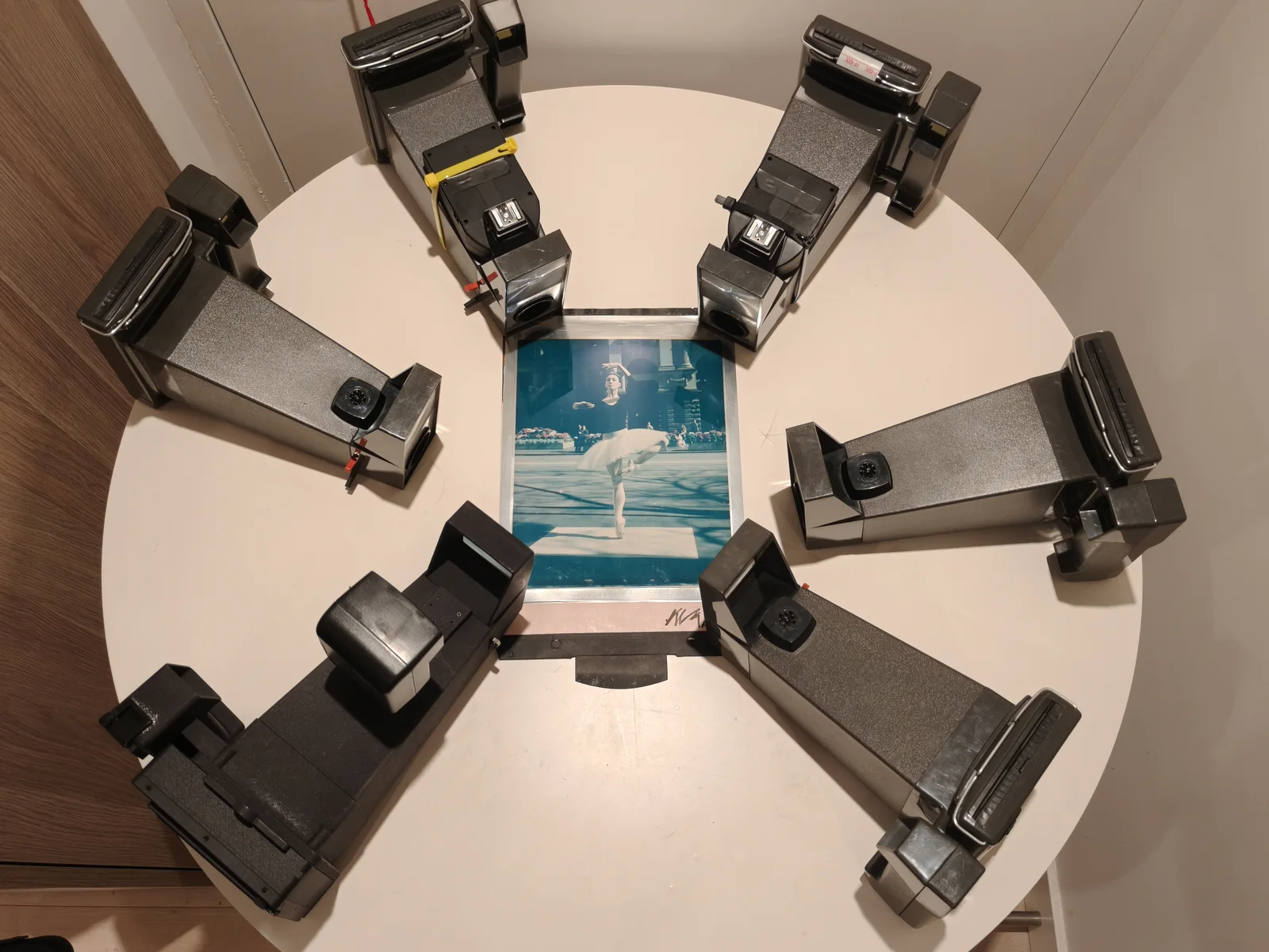 Several instant cameras arranged radially around a central image.