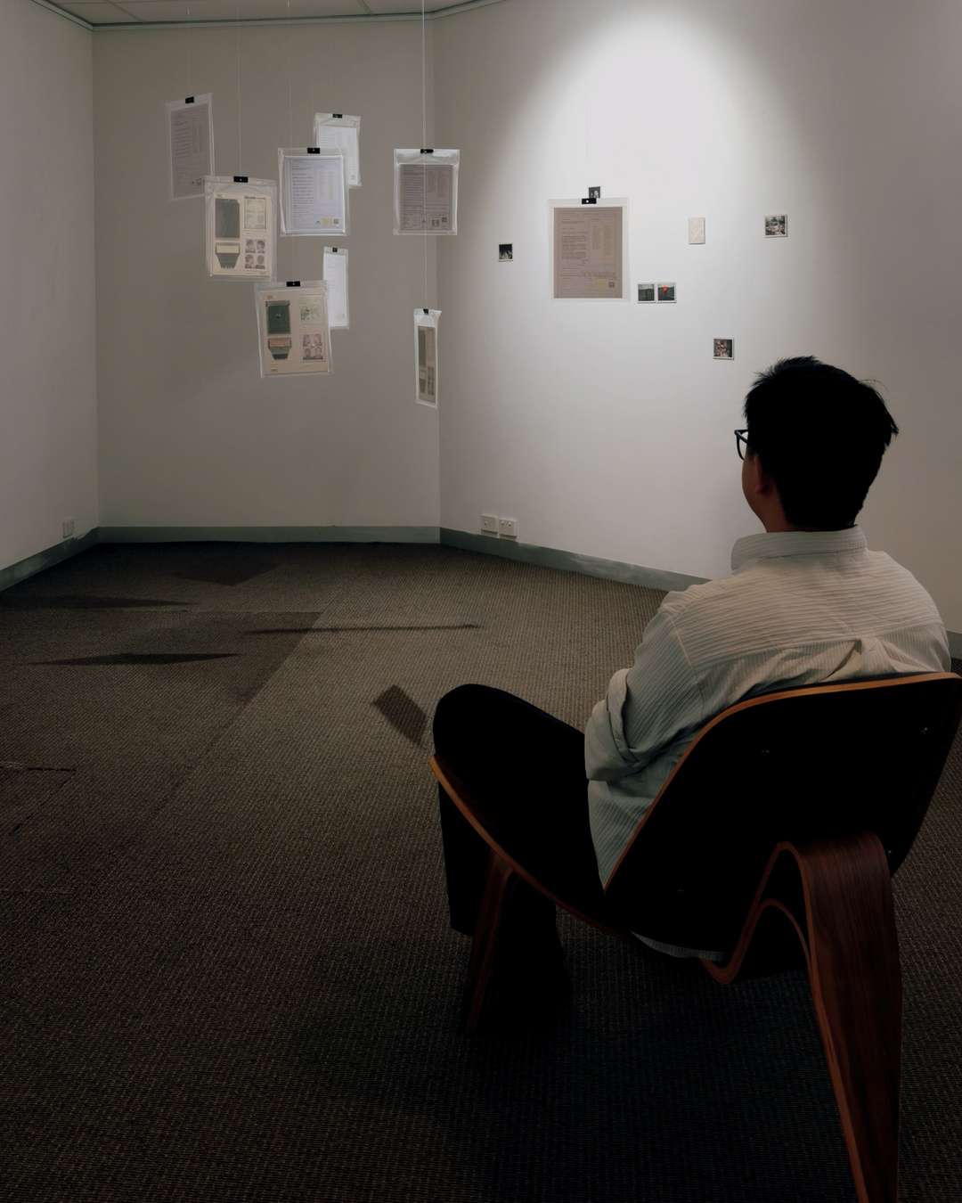 The artist seated facing the suspended records.